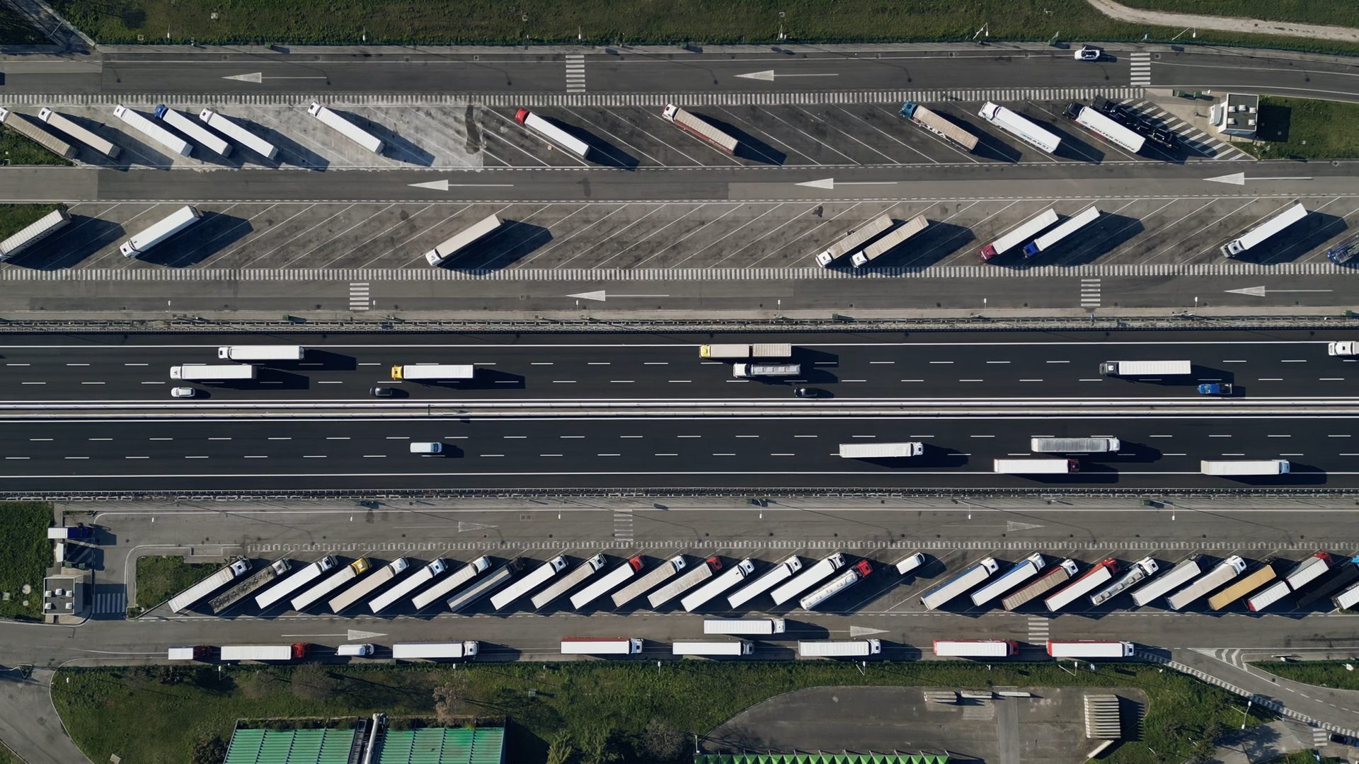 Vista aérea de una autopista con camiones de carga y playas de estacionamiento de un centro logístico.