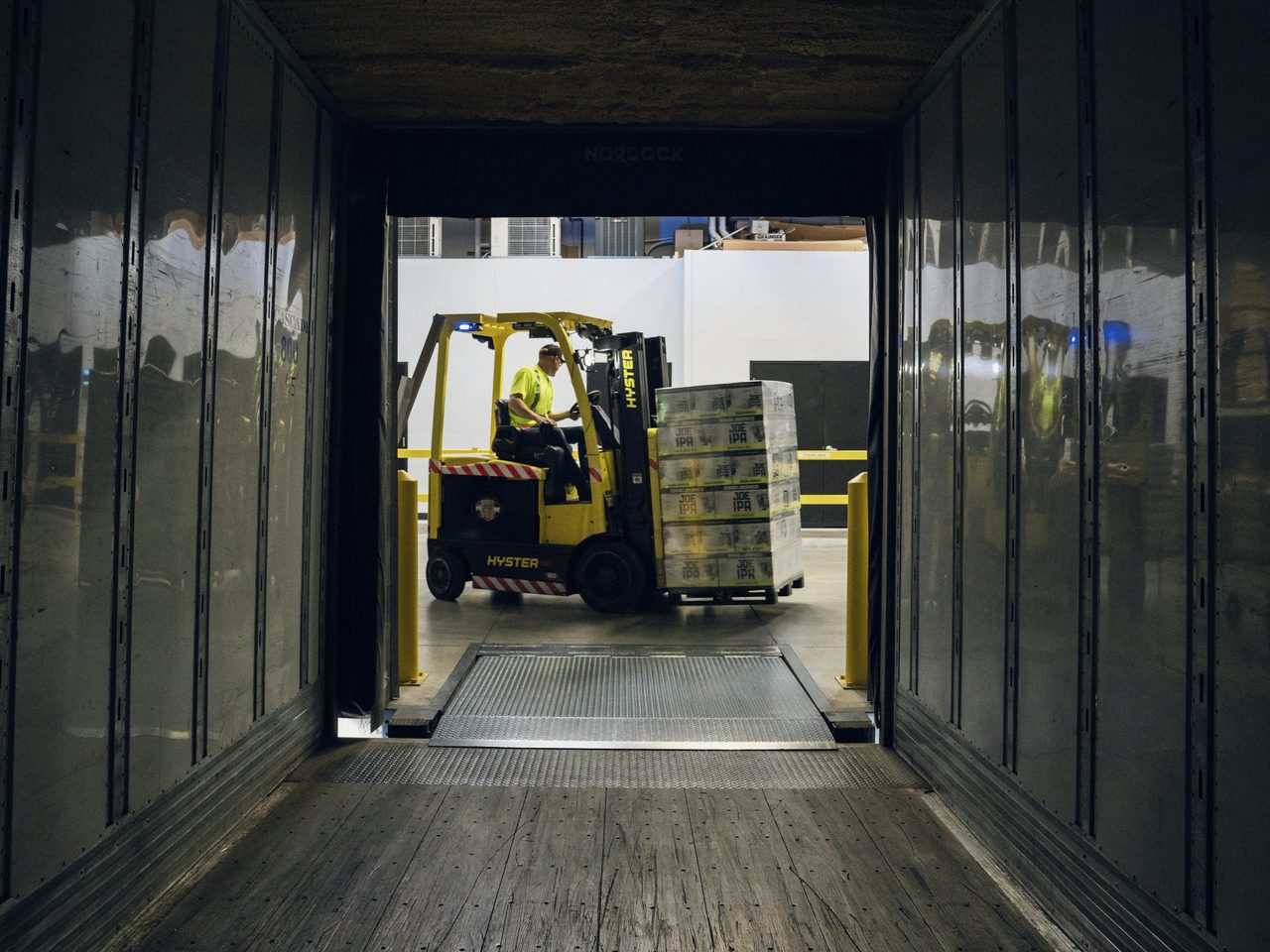 Operario moviendo carga con un autoelevador en un depósito.
